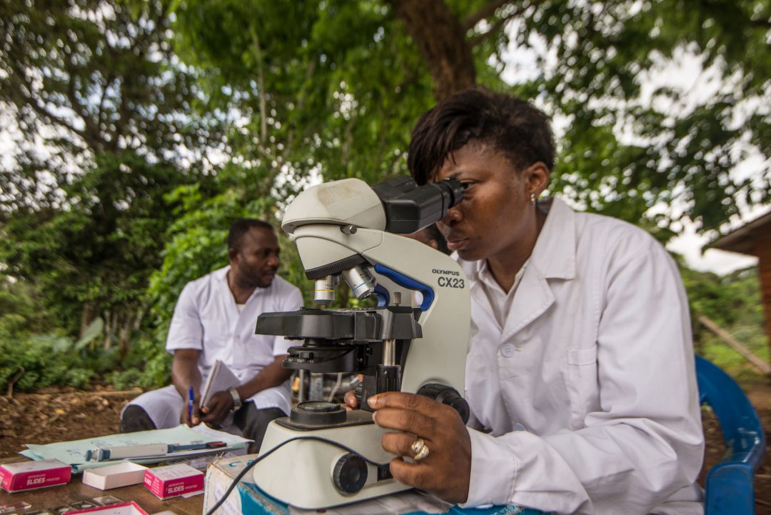 Researcher looks at samples through microscope to detect river blindneess